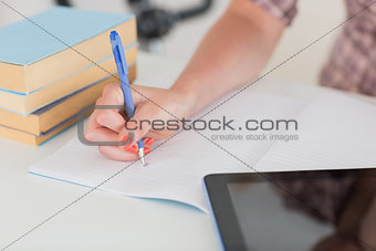 Woman writing on notepad with tablet pc