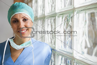 Nurse wearing surgical cap leaning against glass wall