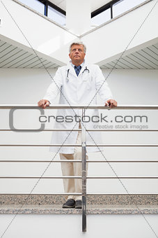 Thinking doctor stands at railing