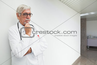 Doctor leaning against wall in corridor and thinking