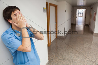 Nurse with hands on face in hospital corridor