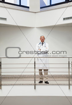 Doctor smiling at the railing with arms crossed