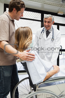 Doctor talking with pregnant woman in wheelchair and partner