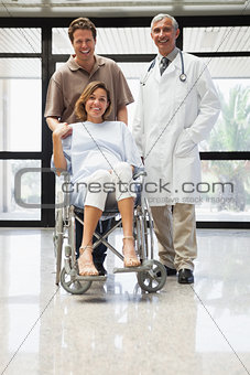 Pregnant woman in wheelchair with partner and doctor smiling
