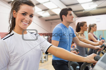 Smiling brunette with other people  on a step machine
