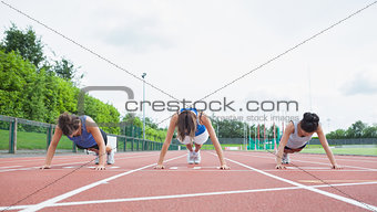 Three women stretching on running track
