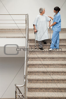 Elderly patient being helped by nurse to go down stairs