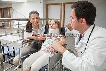 Mother and doctor crouch next to child in wheelchair with neck brace