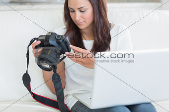 Woman holding a laptop and a camera