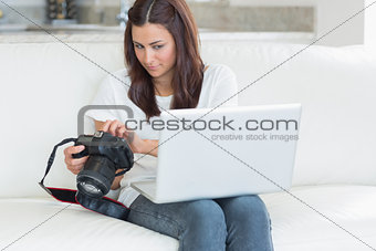 Woman looking at laptop while holding a camera