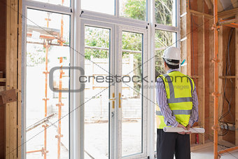Architect holding a plan while looking outside