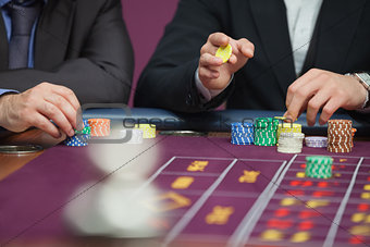 Two men placing roulette bets