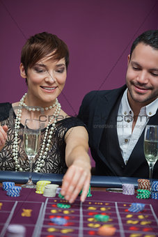 Woman placing roulette bet with man