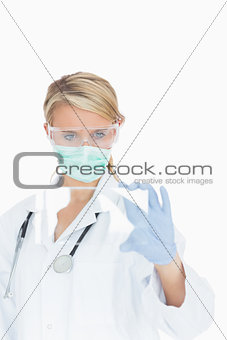 Doctor wearing surgical gear looking at glass pane