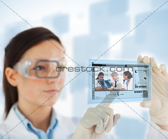Woman pointing on picture of doctor and nurses looking at x ray on hologram interface