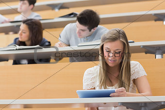 Student sitting at the lecture hall holding a tablet pc