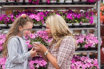 Mother and daughter smelling plant