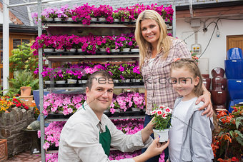 Employee presenting flower pot to little girl with mother