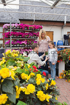 Woman and child taking a flower pot from employee