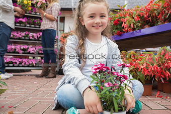 Little girl holding flowers sitting on path