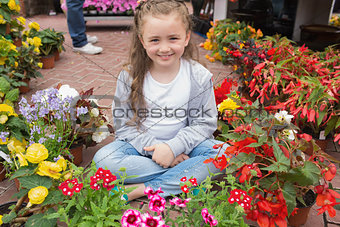 Little girl sitting on path surrounded by flowers