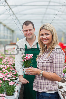 Woman choosing a flower in greenhouse with employee