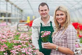 Smiling woman holding flower pot with employee