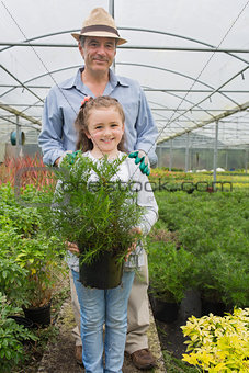Little girl holding potted plant with grandfather