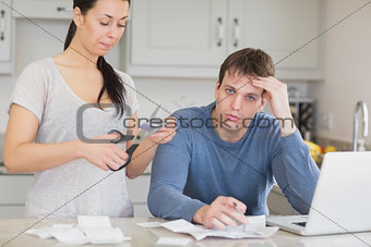 Disappointed woman cutting through a credit card