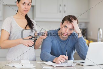 Disappointed couple in the kitchen cutting credit card