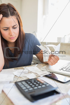 Brunette looking worried and holding bills