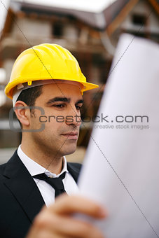 Architect in construction site looking at building plans