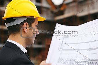Architect in construction site looking at building plans