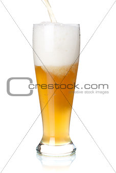 White beer is pouring into a glass from bottle