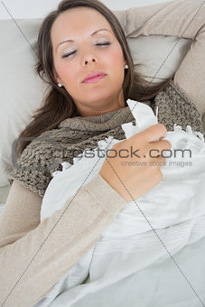 Sleeping woman lying on sofa with a cold