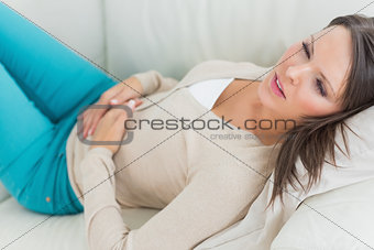Sick woman lying on sofa with stomach ache