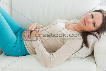 Anxious and sick woman lying on sofa