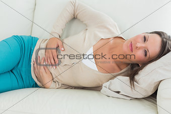 Woman lying on the sofa with upset stomach