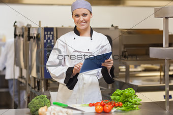 Smiling chef using her digital tablet beside the vegetables