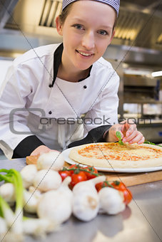 Smiling chef decorating the pizza