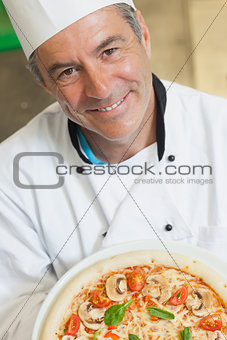 Smiling chef holding a pizza
