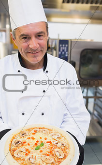 Smiling chef showing pizza