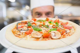 Cook presenting a pizza