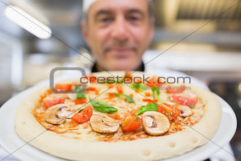 Chef holding pizza up