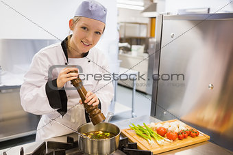 Cheerful woman spicing soup