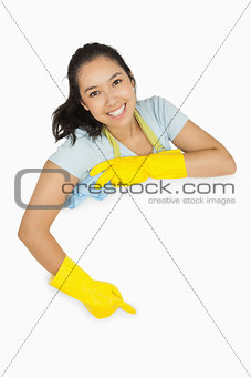 Happy cleaning lady pointing to white surface