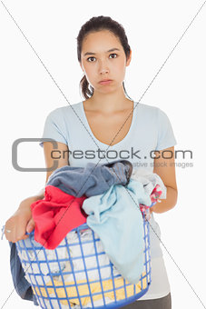 Bored woman holding a basket overflowing of laundry