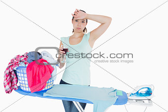 Woman drinking wine and ironing clothes