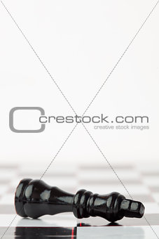 Black chessman lying at the chessboard