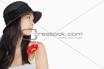 Cheerful woman with flower looking away wearing a hat